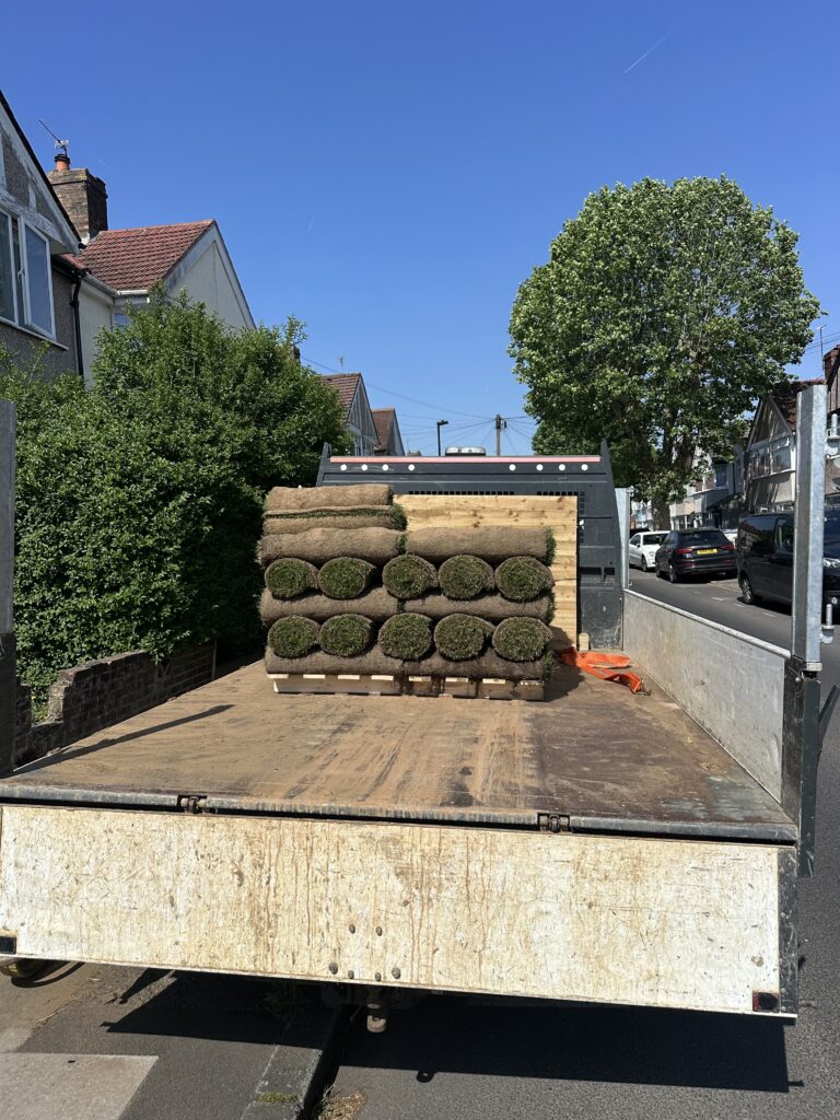 Rolls of fresh turf loaded onto a flatbed truck, ready for delivery and installation at a residential garden landscaping project in London