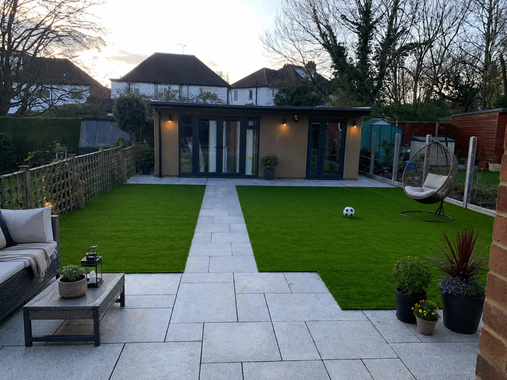 Modern garden with fresh artificial grass, porcelain paving, contemporary garden room, outdoor seating, hanging egg chair, and potted plants in a landscaped London garden.
